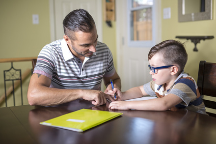 Jeune qui fait ses devoirs aidé d'un adulte